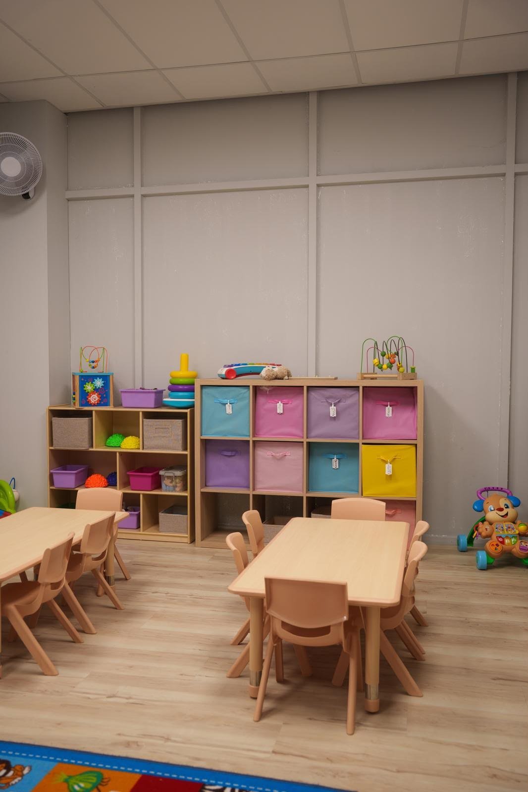 Organized classroom with child-sized tables and colorful storage