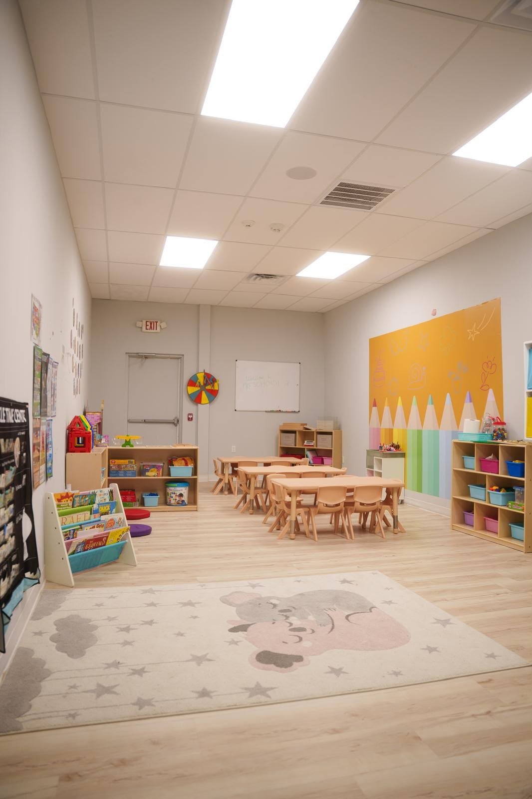 Bright preschool classroom with learning tables, books and activity areas